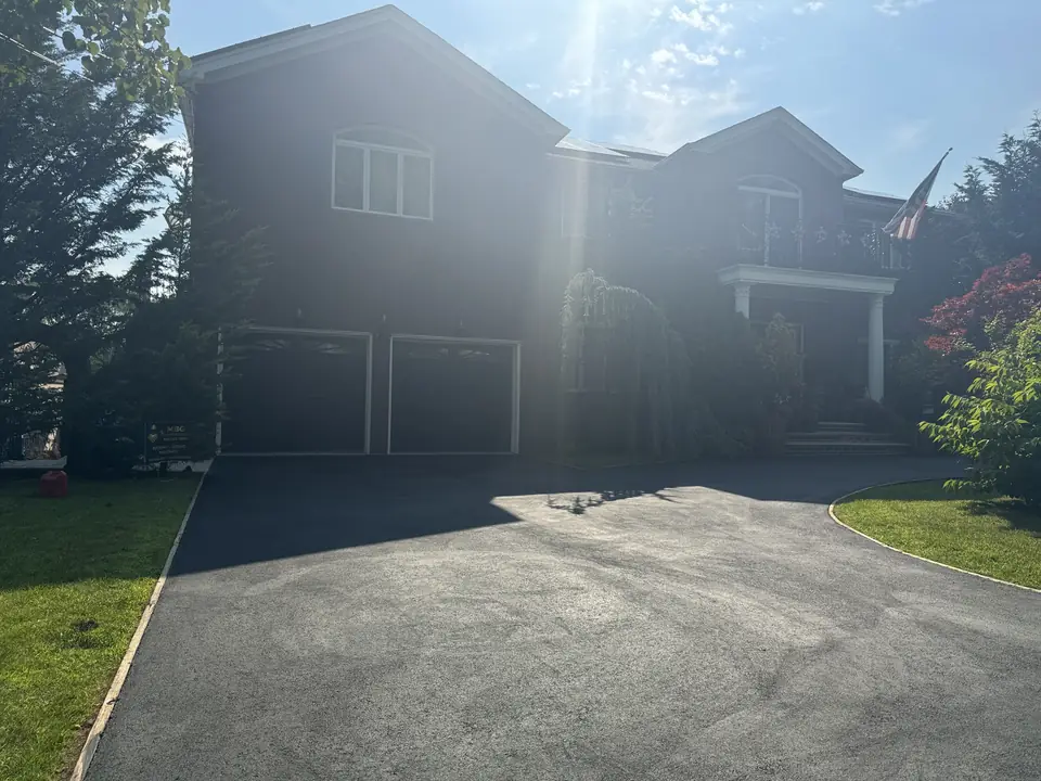 Wide asphalt driveway leading to a two-car garage