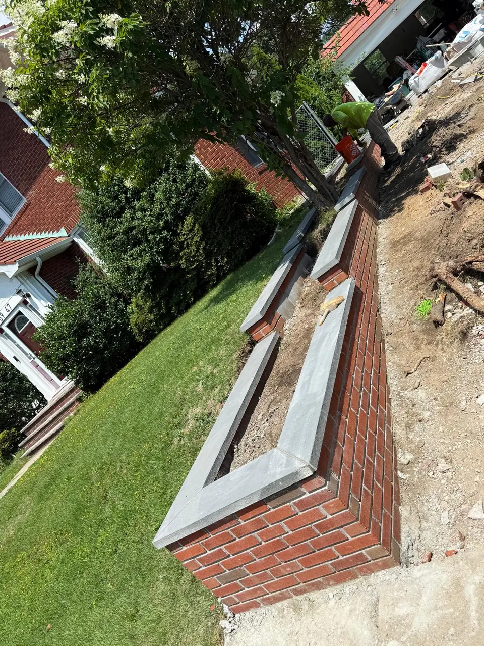 Brick retaining wall with caps along a lawn