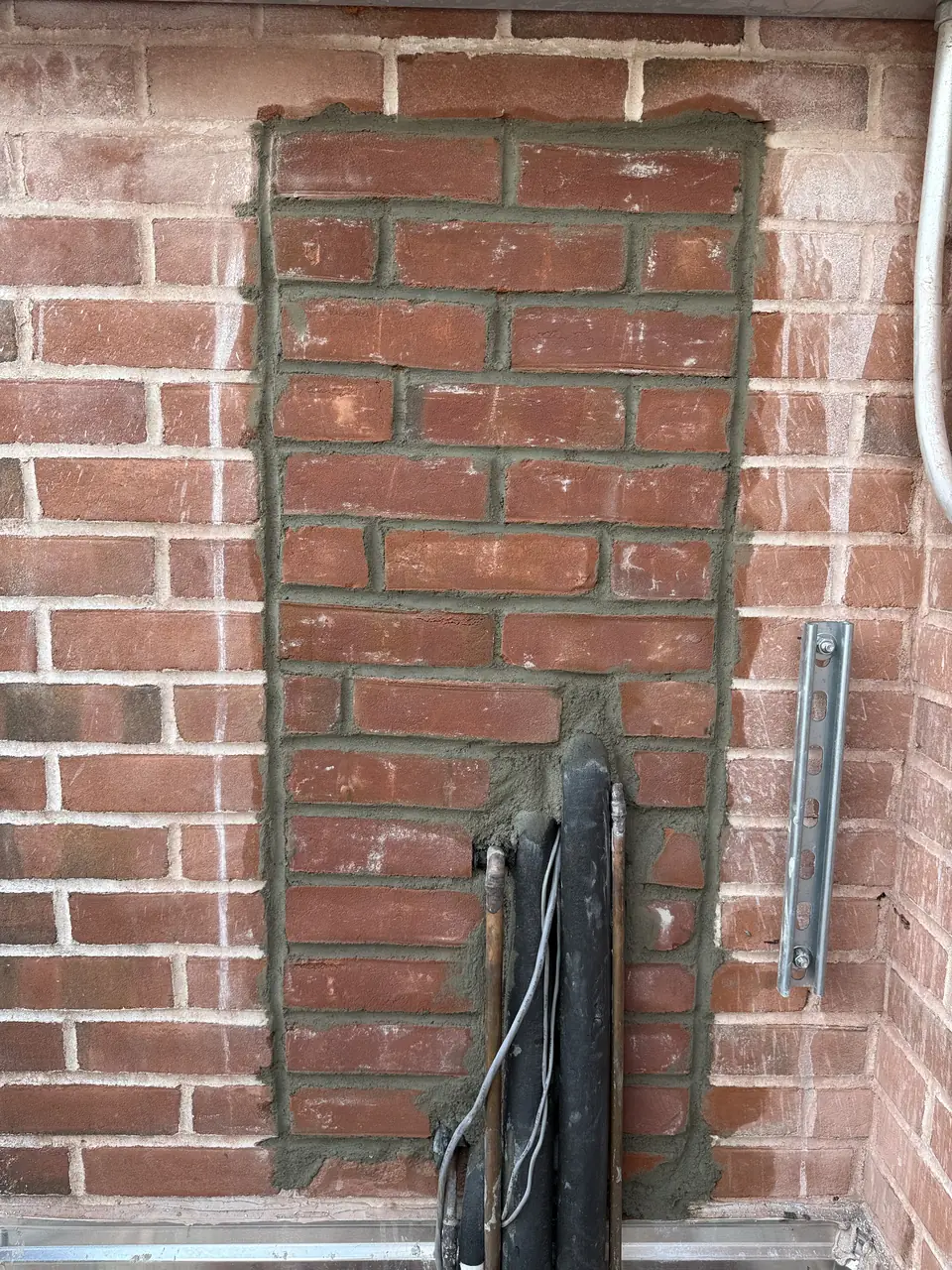 Section of brick wall rebuilt around utility lines