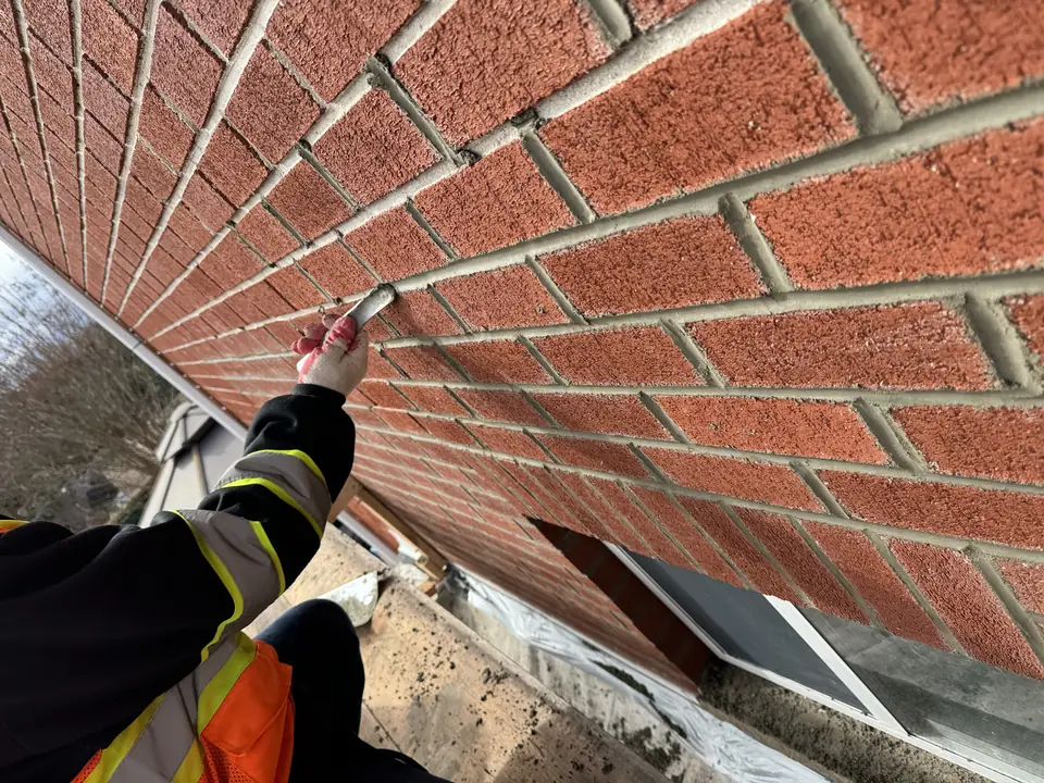 Close-up of fresh mortar being tooled into brick joints
