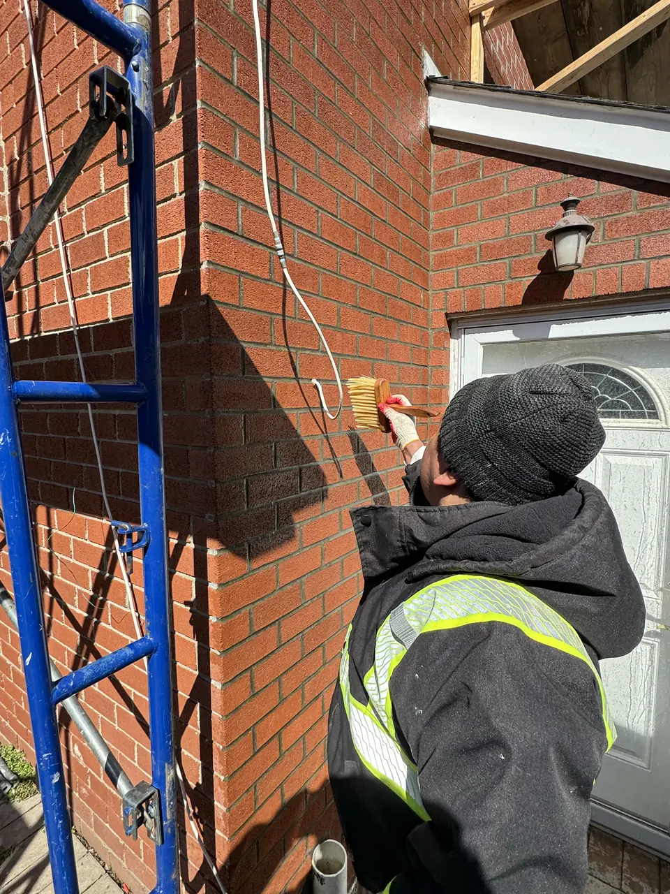 Mason pointing a brick wall next to a front door
