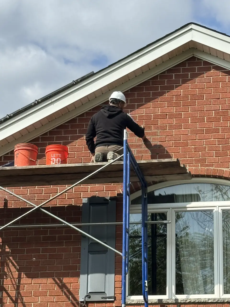 Mason on scaffolding pointing a brick gable