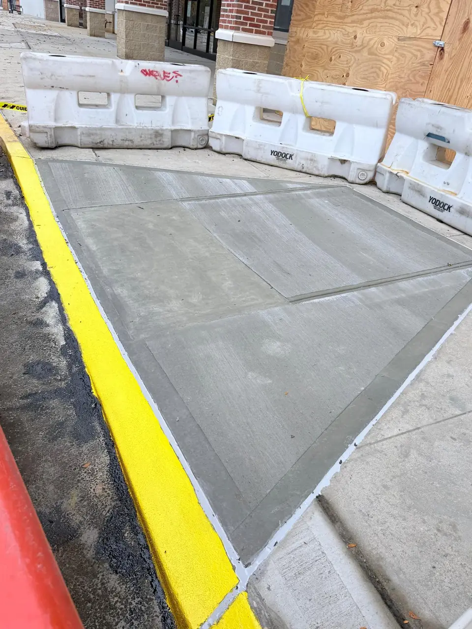 New commercial sidewalk section with barriers and painted curb