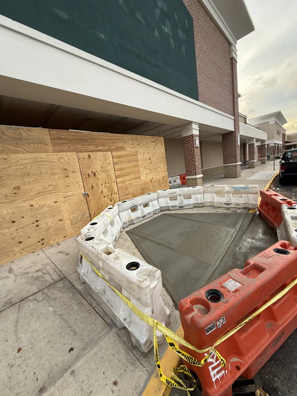 Fresh sidewalk pour protected by barriers outside a storefront